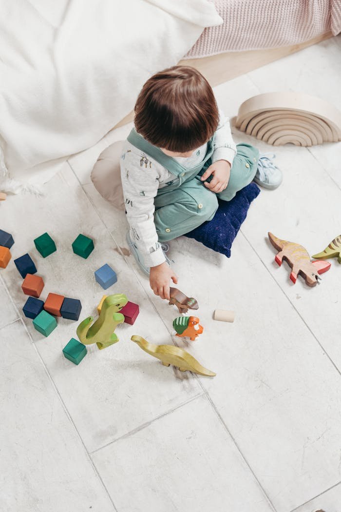 A young child engaged in play with colorful wooden toys on a tiled floor indoors.