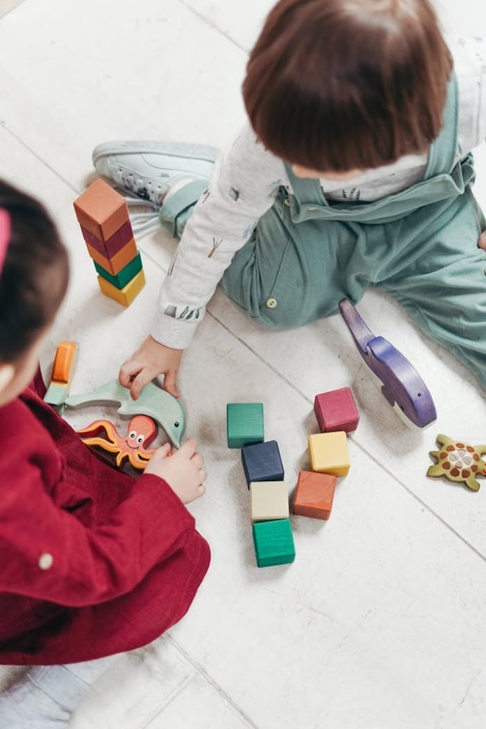 Two young children playing with colorful wooden blocks indoors, fostering creativity and fun.